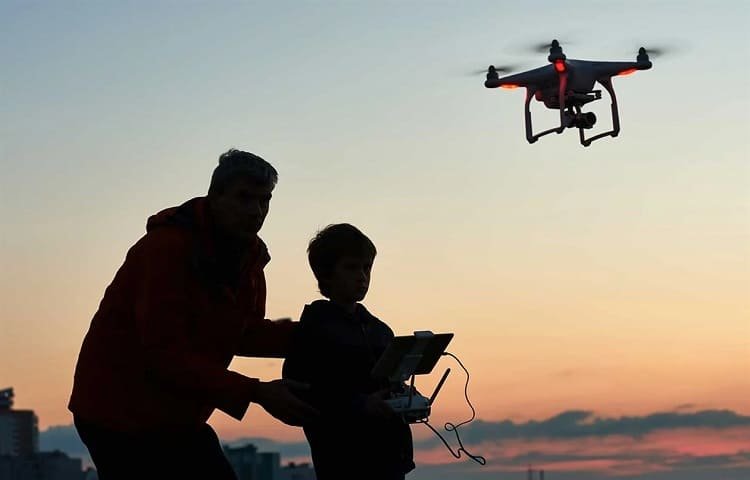 boy flying camera drone with dad