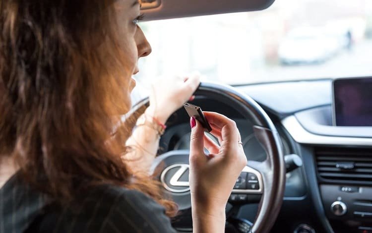 woman in car with voice recorder